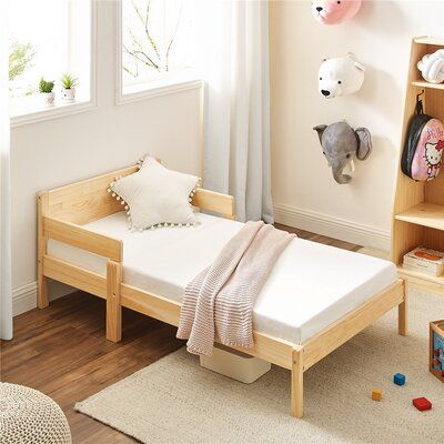 a small child's bed in a room with toys on the floor and bookshelves