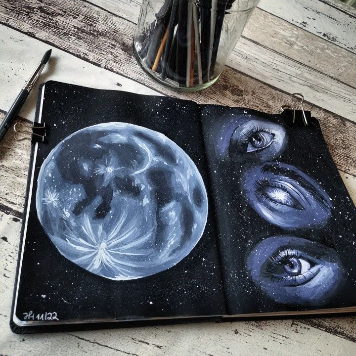 an open notebook with two images of the moon and stars on it next to some pens