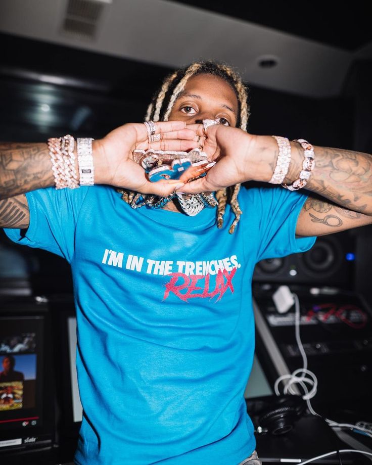 a man with dreadlocks holding his hands up in front of his face while wearing a blue shirt