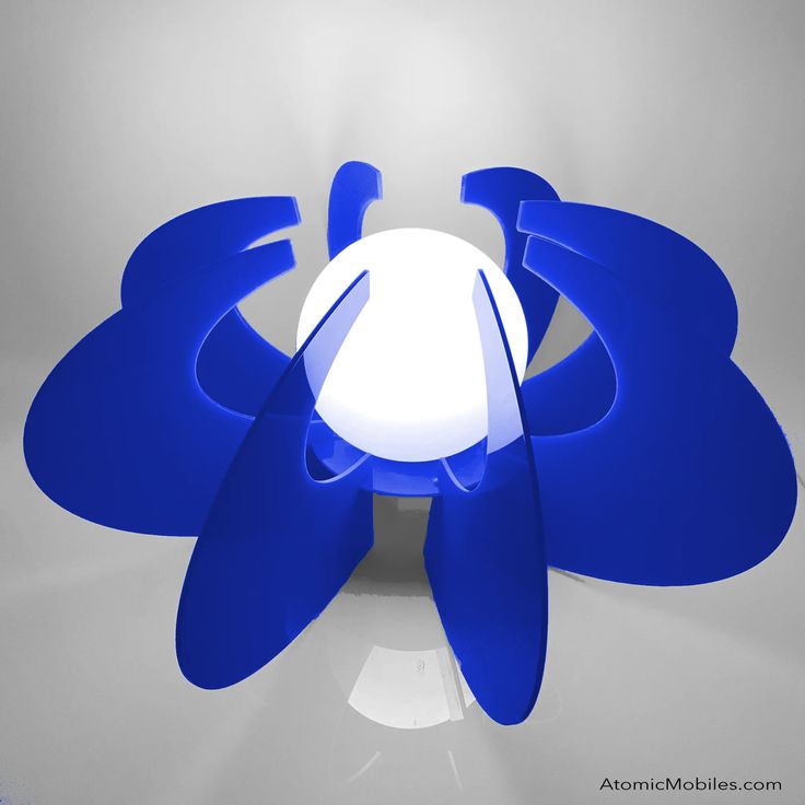 a blue flower lamp sitting on top of a white table next to a gray wall