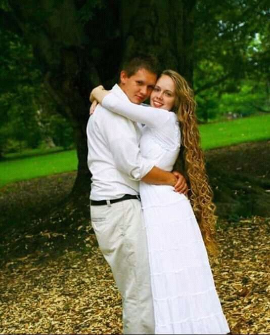 a man and woman hugging in front of a tree