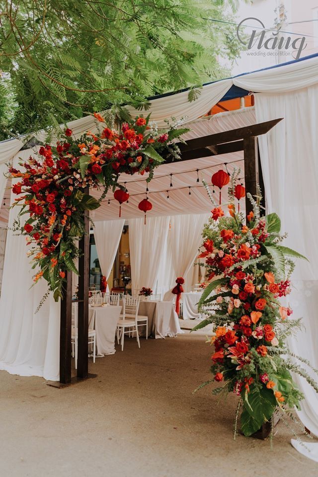 an outdoor wedding venue with white drapes and red flowers