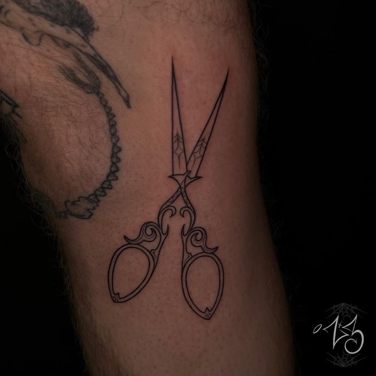 a pair of scissors tattoo on the arm