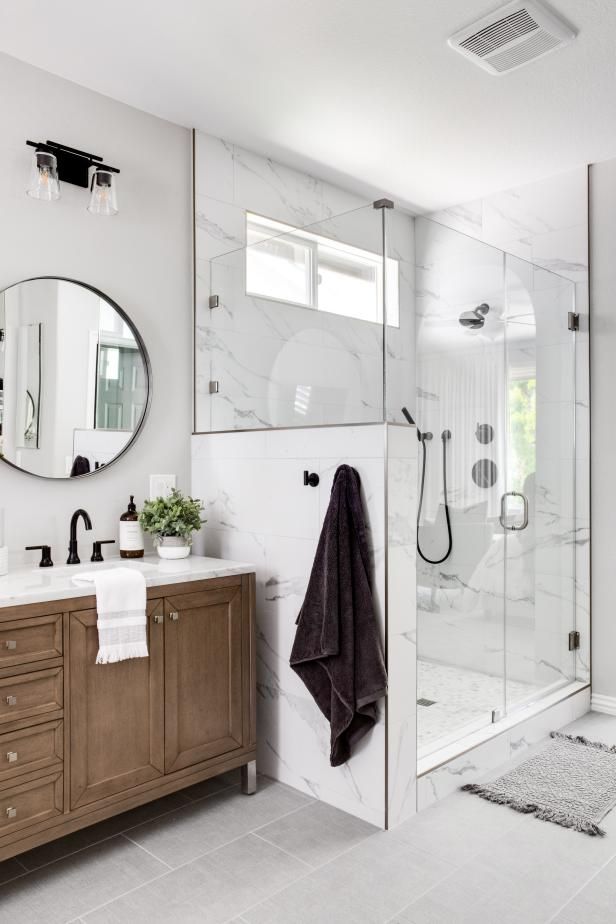 a white bathroom with marble counter tops and wooden cabinets, along with a walk in shower