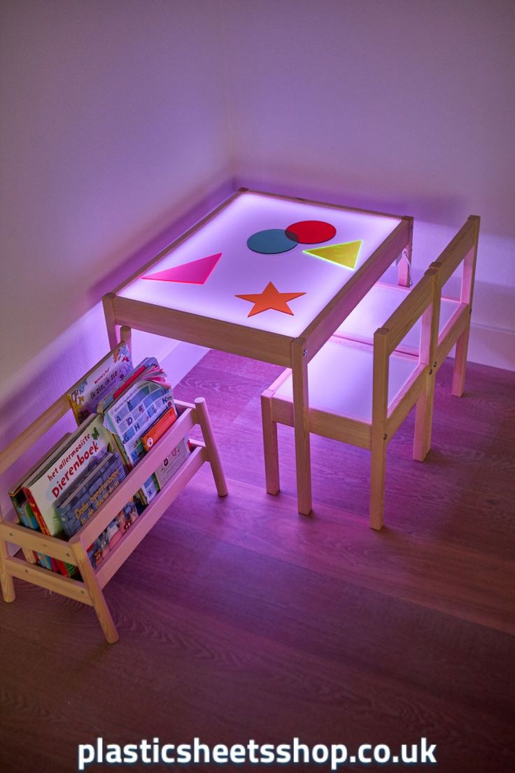 an illuminated table and bench with books on it in a room that has hardwood floors