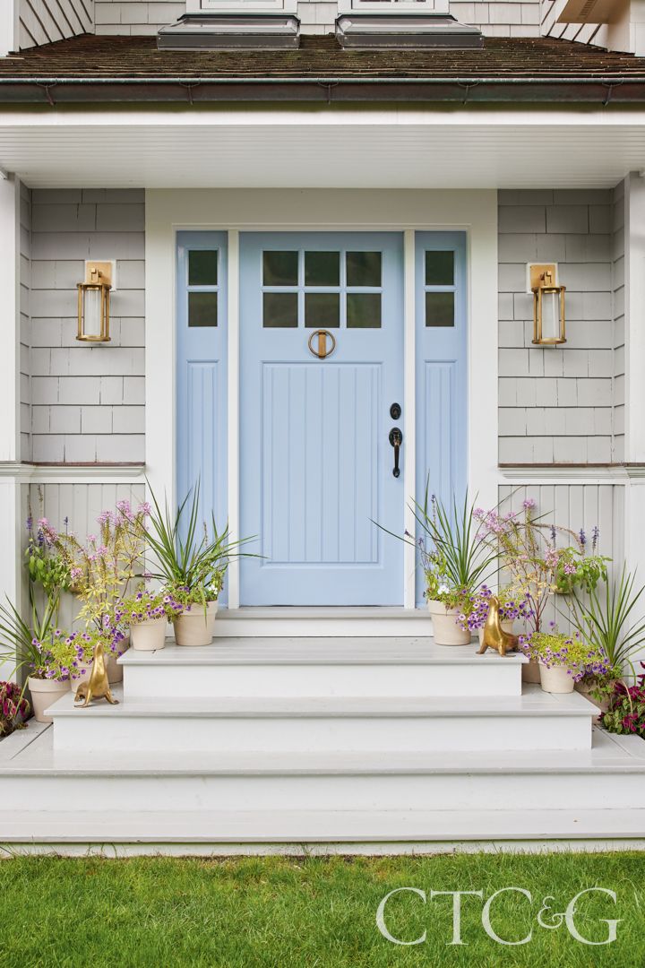 a blue front door with potted plants and flowers on the steps in front of it