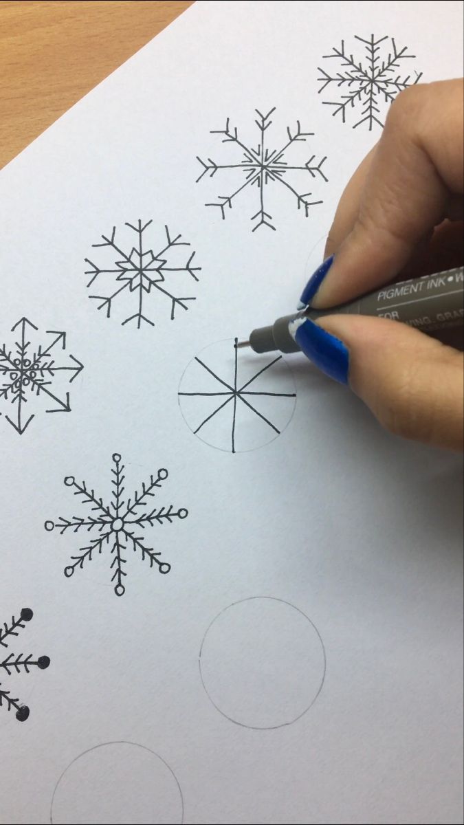 someone is drawing snowflakes on the paper