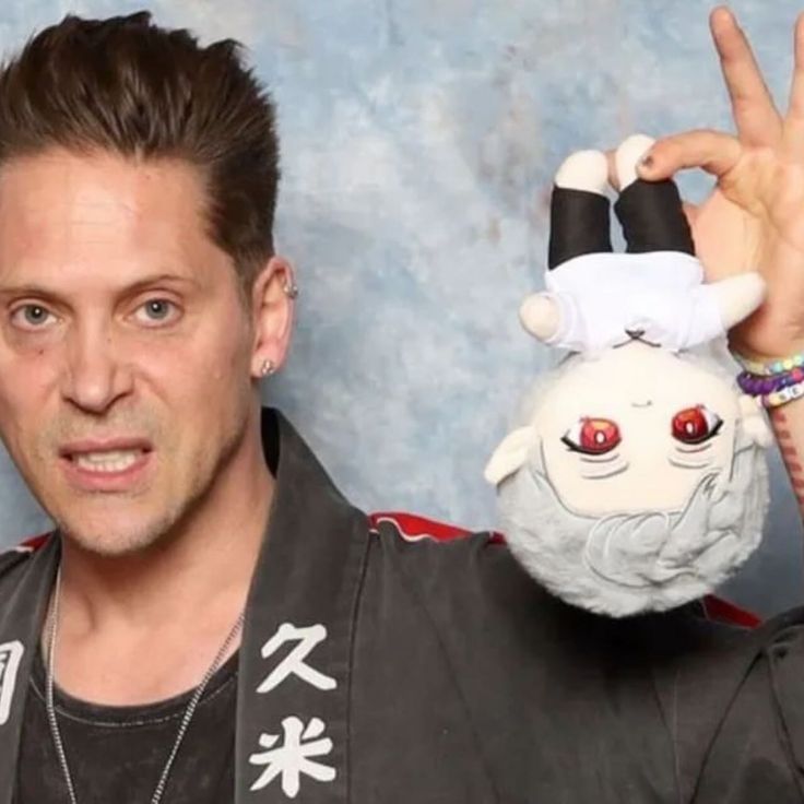 a man holding up a stuffed animal in front of his face and making the peace sign