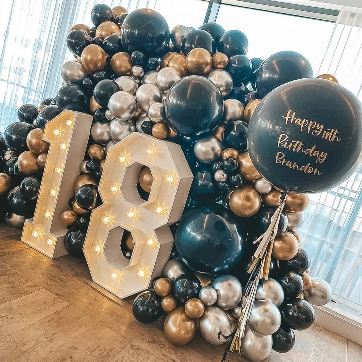 the balloon arch is decorated with black, silver and gold balloons that spell out happy 18th birthday