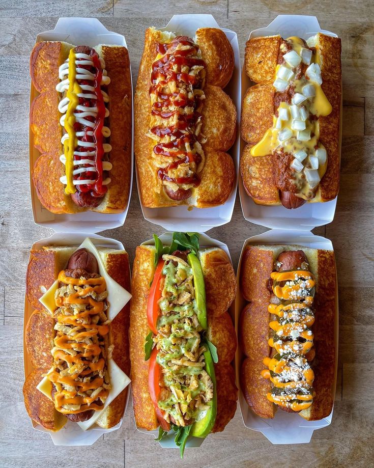 six hotdogs with different toppings and condiments arranged in trays