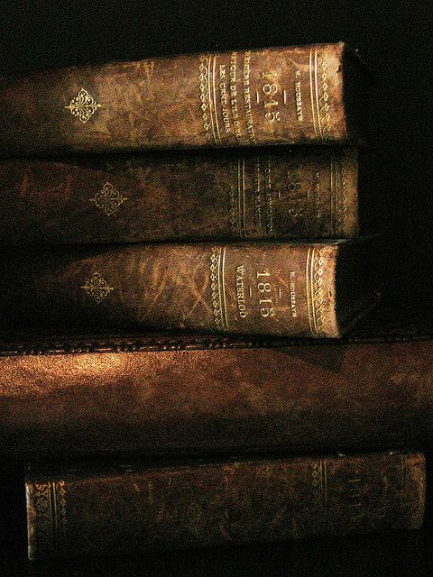 three old books are stacked on top of each other in front of a black background