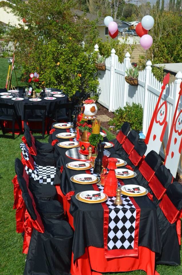 a table set up with black and white checkered cloths, red napkins, and plates