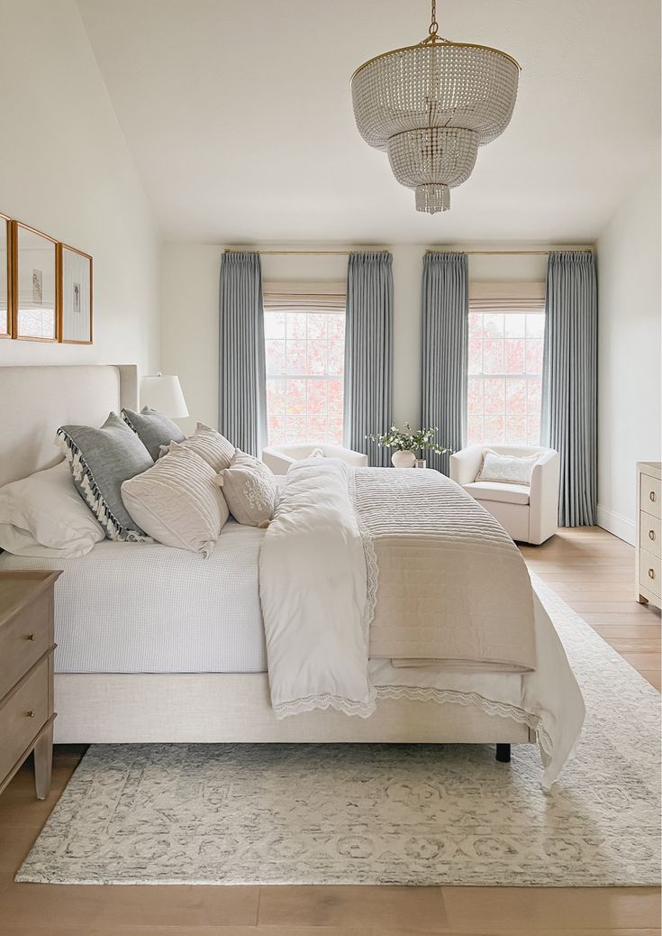 a large white bed sitting in a bedroom next to a window with blue drapes