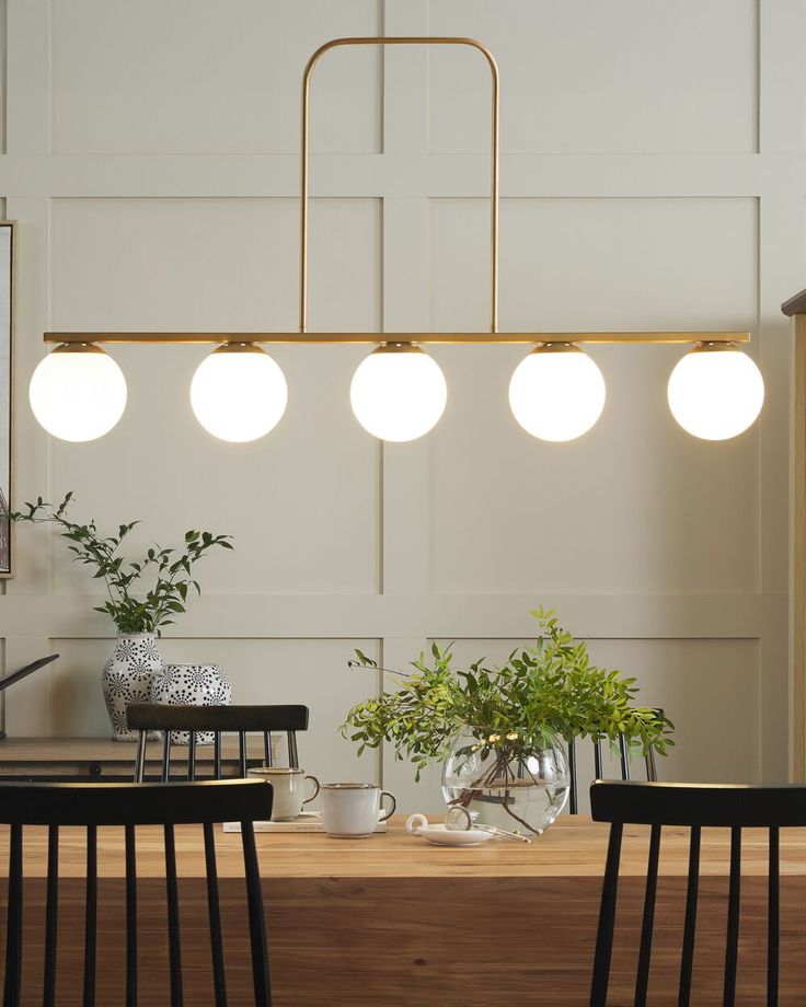 a dining room table with four chairs and three lights hanging from the ceiling over it