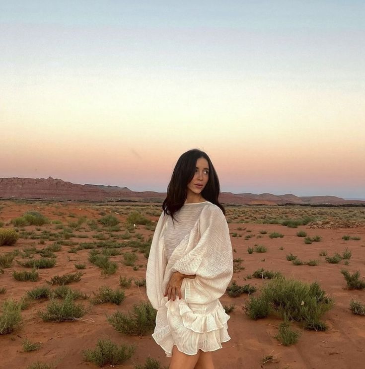 a woman standing in the middle of a desert