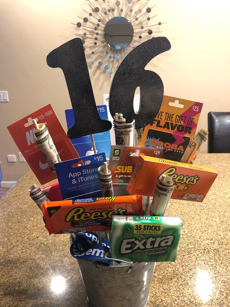 a bucket filled with lots of different types of snacks and candy in front of a clock