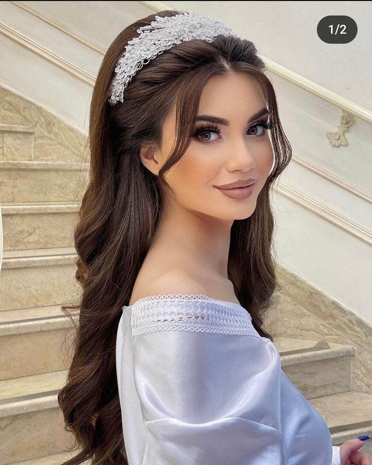 a woman with long hair wearing a tiara on her head and standing in front of some stairs