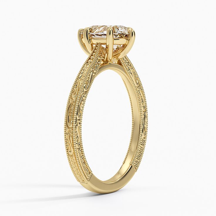 a yellow gold engagement ring with an intricate design and two round diamonds on the side