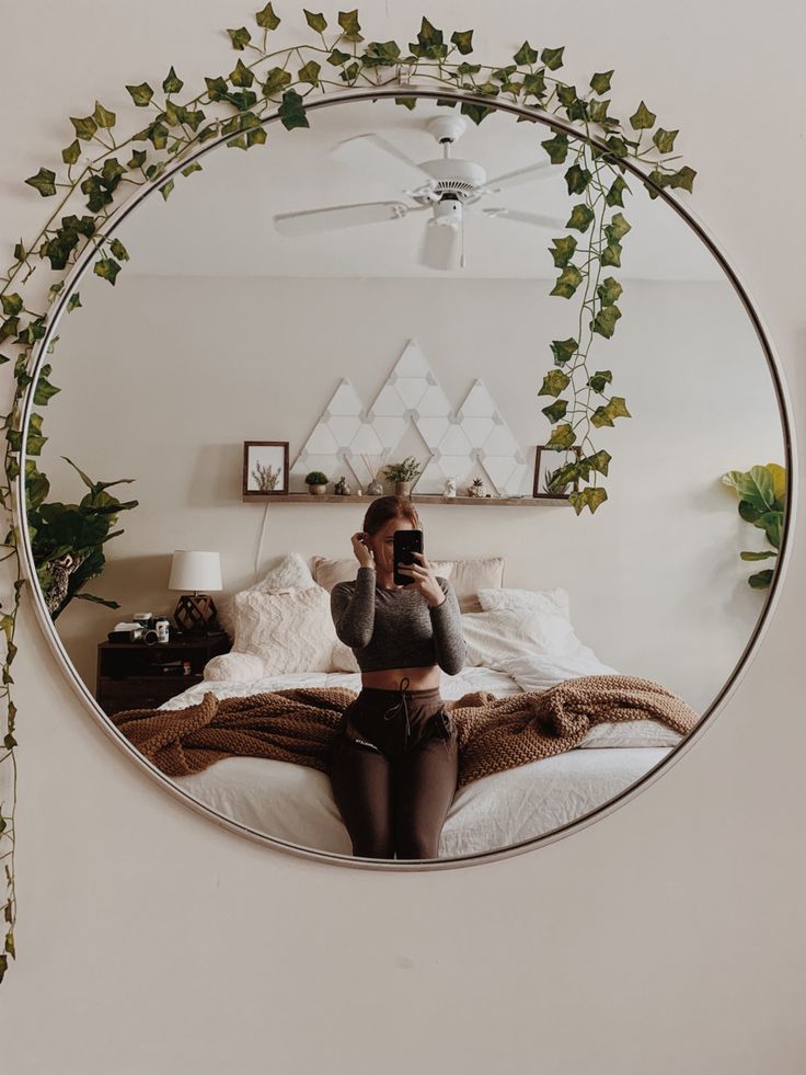 a woman taking a selfie in front of a mirror with ivy growing on it