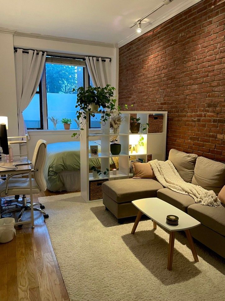 a living room filled with furniture and a brick wall behind the couch is a bed