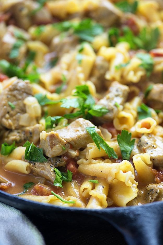 a skillet filled with pasta, meat and vegetables