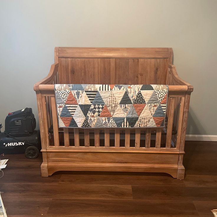 a wooden crib with a quilt on it