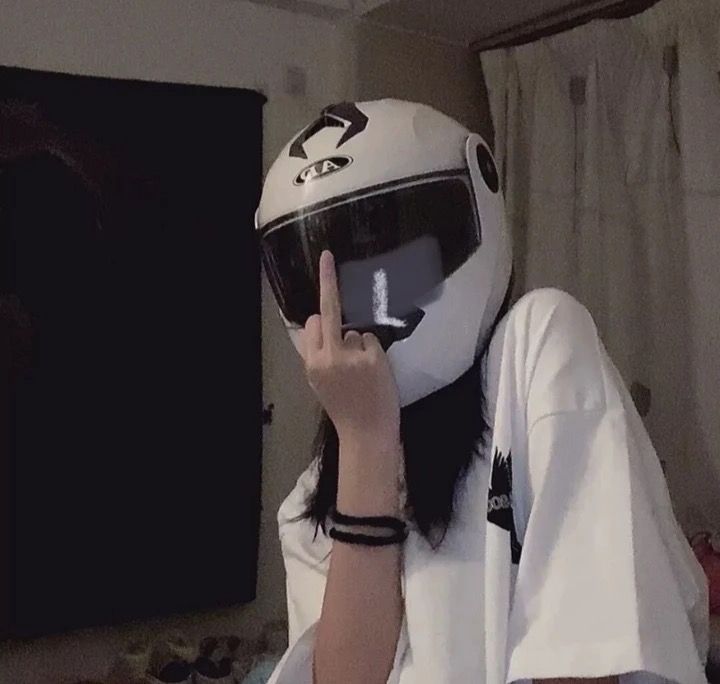 a person wearing a white shirt and black helmet making the peace sign with their hand