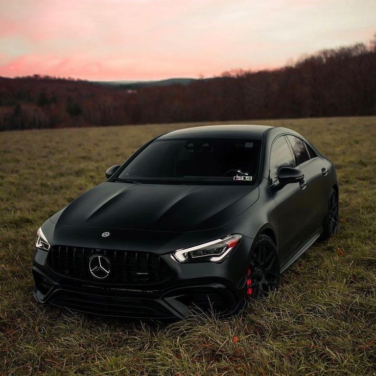 a black sports car parked in the middle of a grassy field at sunset or dawn