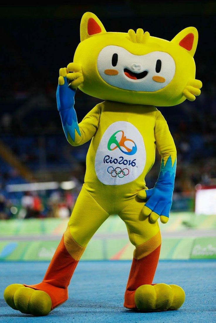 a mascot in a yellow cat suit is standing on the blue carpet at an olympics event