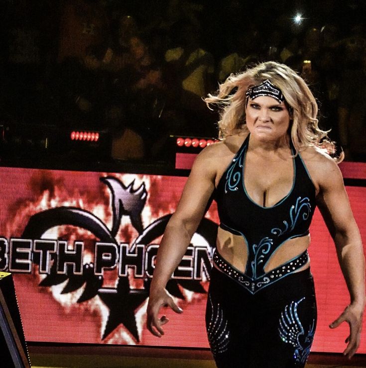 a woman in a wrestling outfit is walking on the stage with her hands behind her back