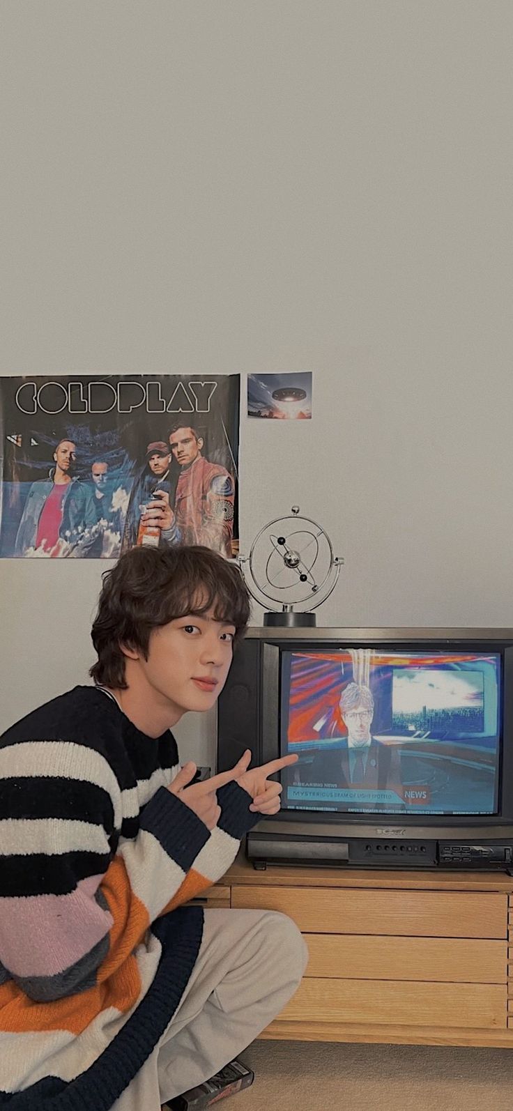 a young man sitting on the floor in front of a tv pointing at something with his finger