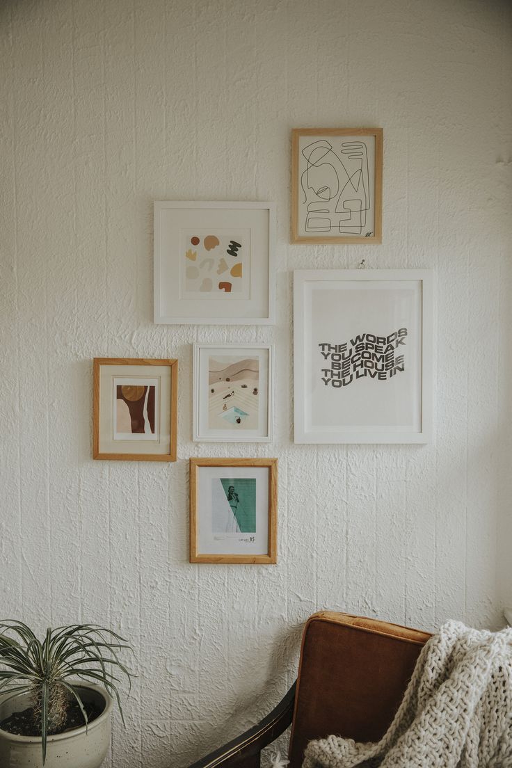 a chair sitting in front of a white wall with pictures on the wall above it