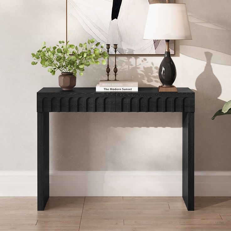 a black console table with two plants on top and a white lamp next to it