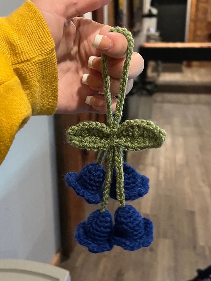 a person holding up a small crochet decoration