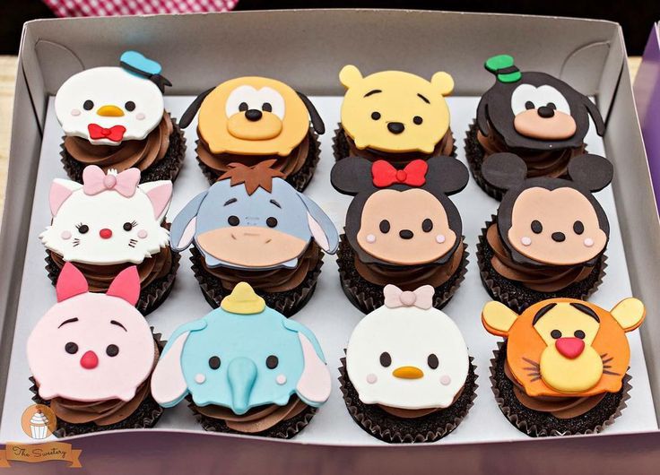 a box filled with lots of cupcakes covered in frosting and cartoon characters