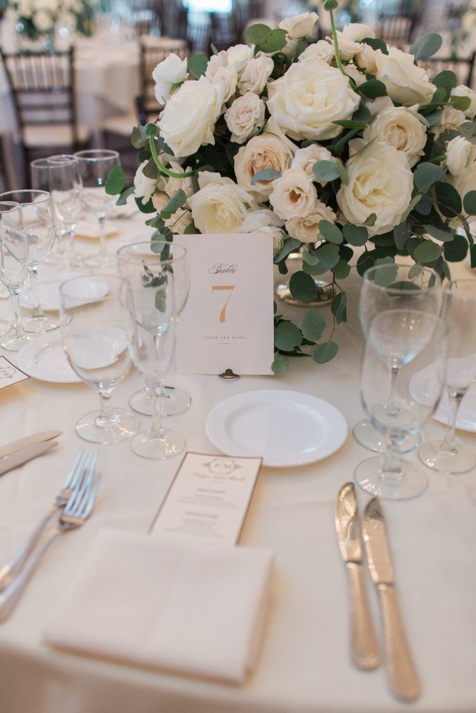 the table is set with white flowers and silverware