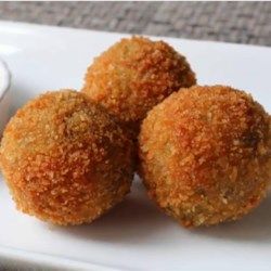 three fried food items on a white plate with a small bowl of dip in the background