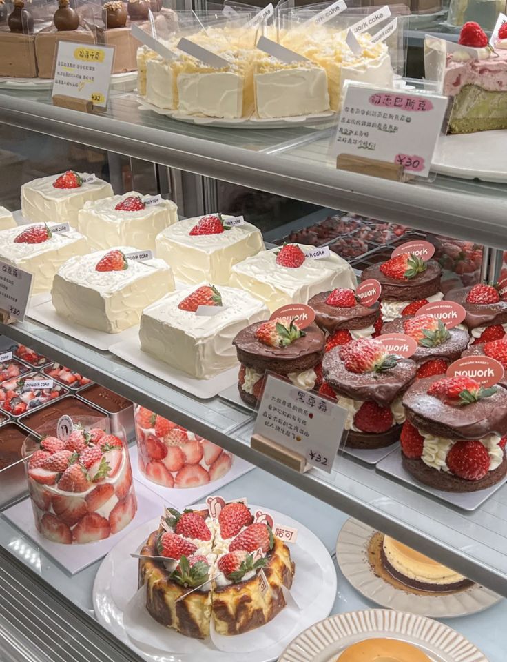 a display case filled with lots of different types of cakes and desserts on plates