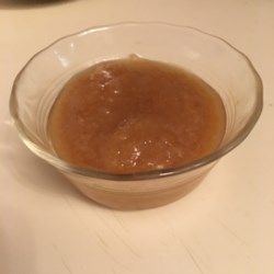 a glass bowl filled with brown liquid sitting on top of a white counter next to a knife