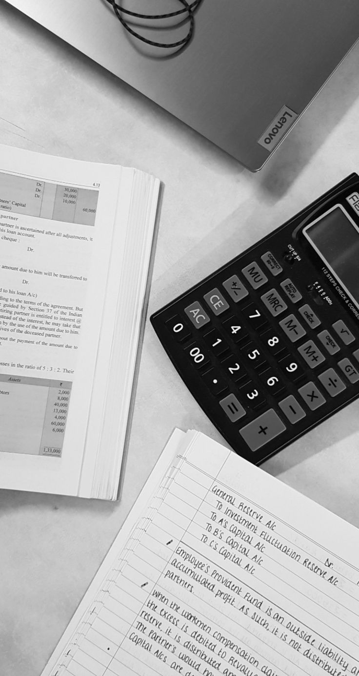 a calculator sitting on top of an open book next to a laptop computer