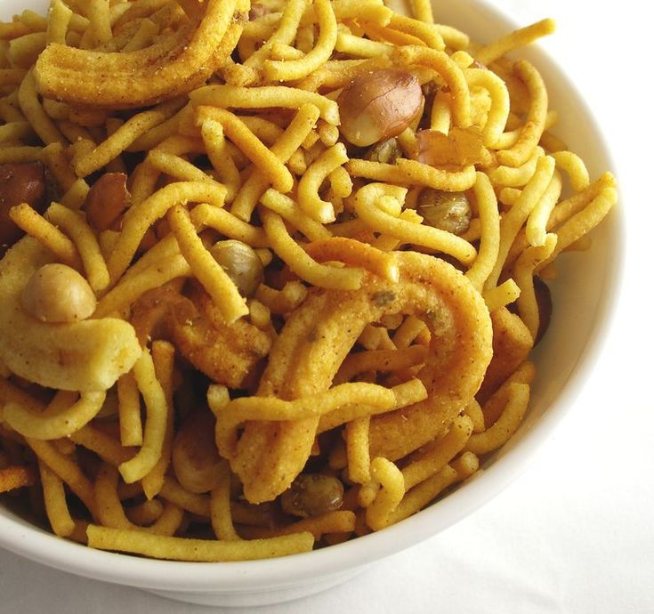 a white bowl filled with noodles and meat on top of a blue and pink background