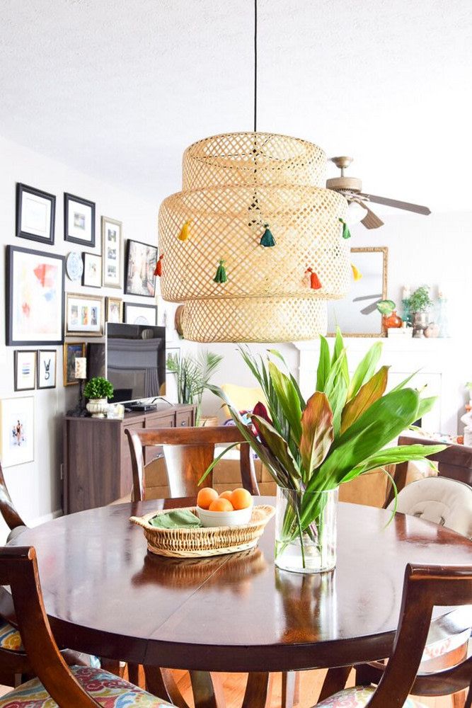 a dining room table with chairs and a bowl of fruit on it in front of a chandelier