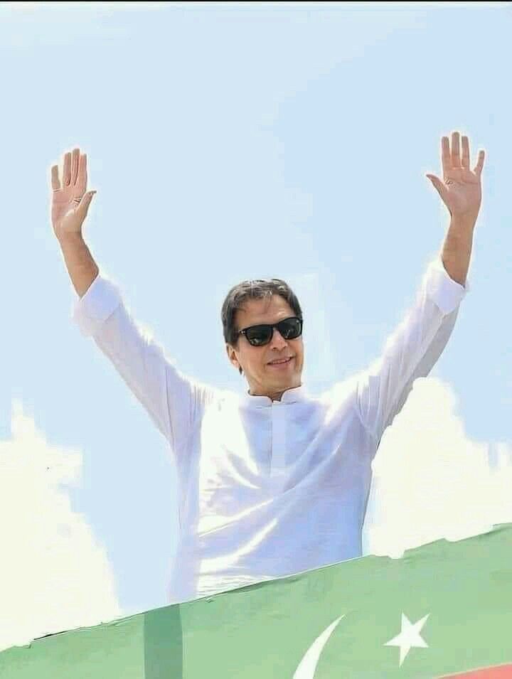 a man with his hands up in the air while standing on top of a flag