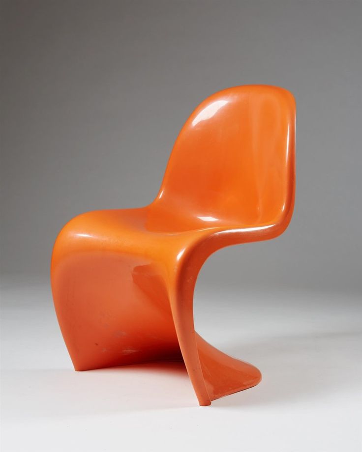 an orange plastic chair sitting on top of a white floor next to a gray wall