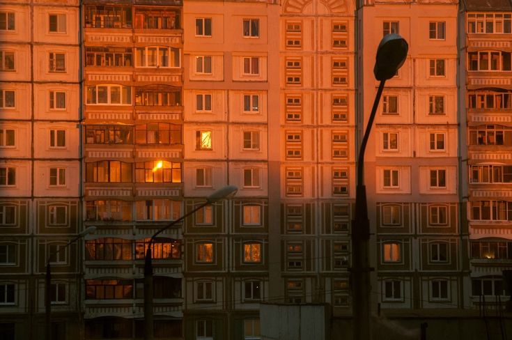 the sun is setting in front of an apartment building with many windows and balconies