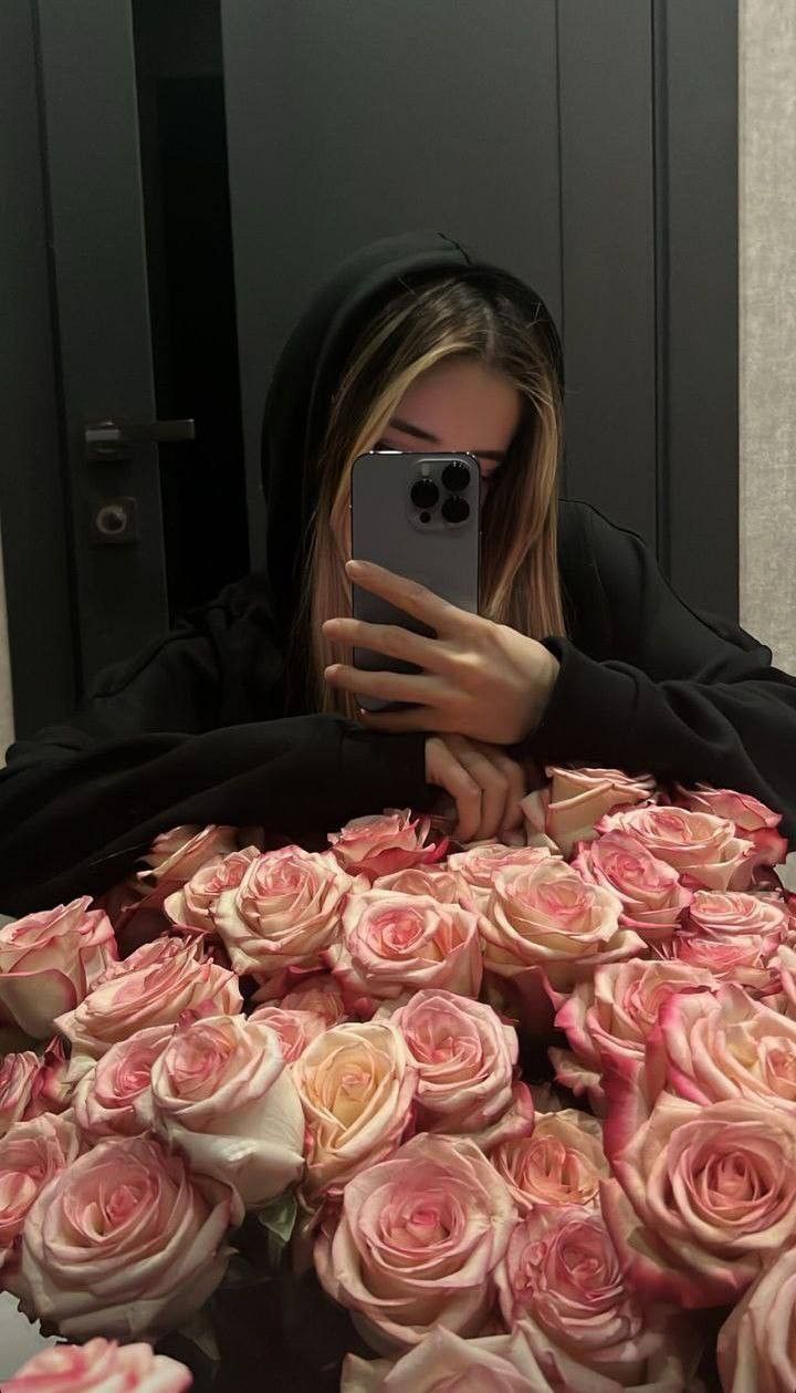 a woman taking a selfie while surrounded by roses