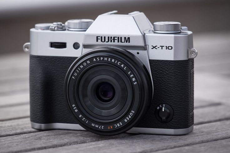 a silver camera sitting on top of a wooden table next to a black and white lens