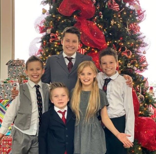 a group of young children standing next to each other in front of a christmas tree