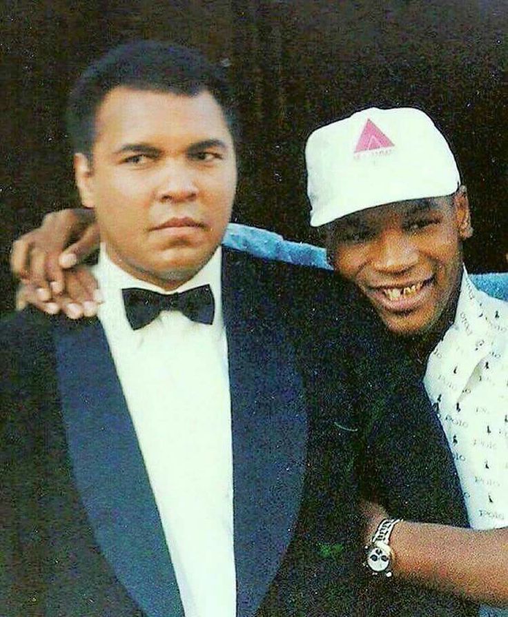 two men in tuxedos are posing for a photo with one man wearing a white hat