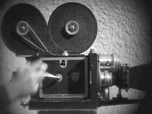 an old fashioned movie camera being held by someone's hand in black and white